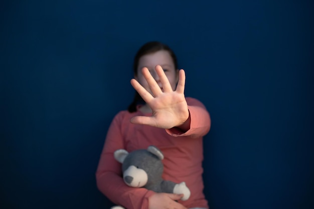 Close-up of woman holding heart shape against blue background