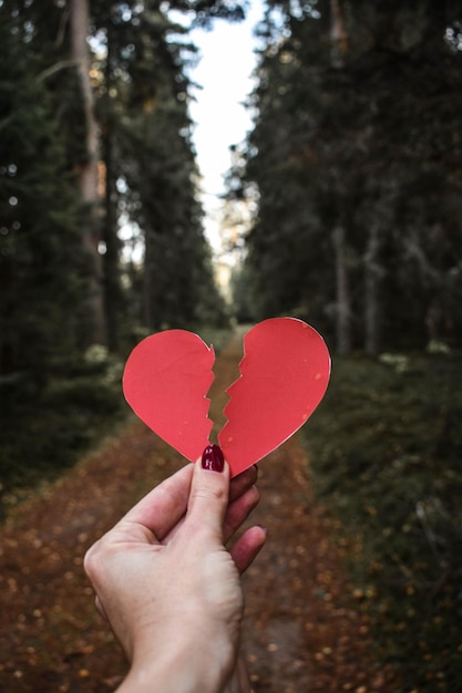 Foto close-up di una donna che tiene in mano una forma di cuore all'aperto