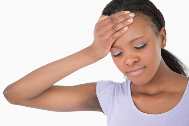 Close up of woman holding her forehead against white background