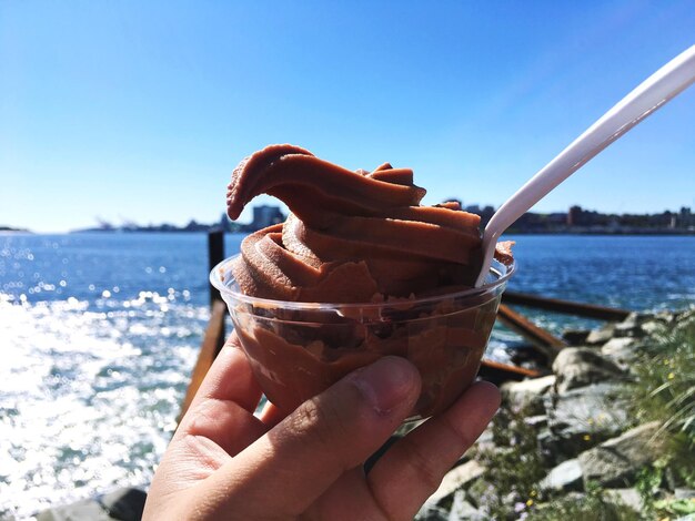 Close-up of woman holding ice cream against sea