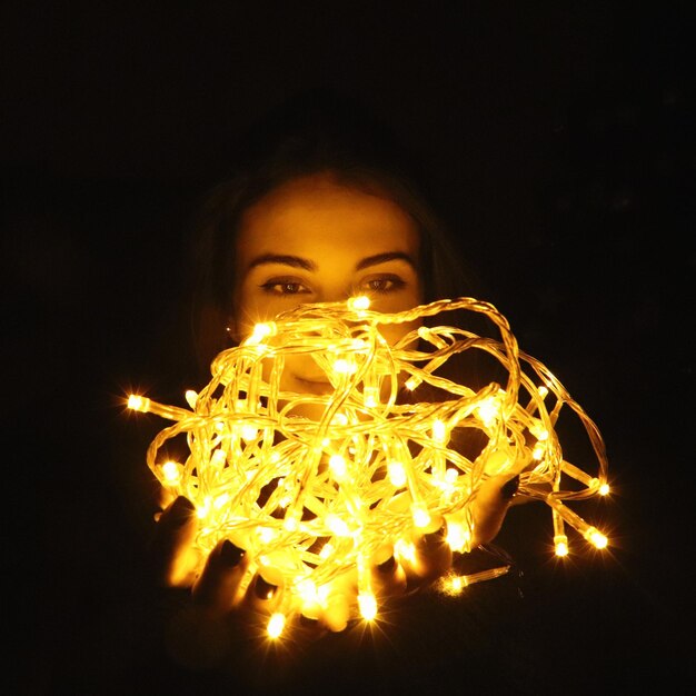 Foto close-up di una donna che tiene le luci illuminate in una camera oscura