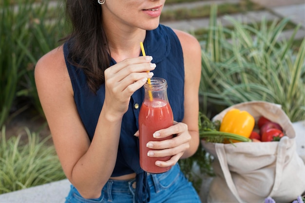 Foto primo piano donna che tiene in mano una bottiglia di succo