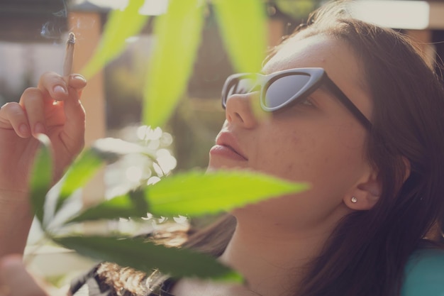 Photo close-up of woman holding marijuana joint by plant