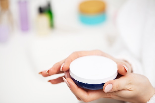 Close up of woman holding moisturizer for facial skin care