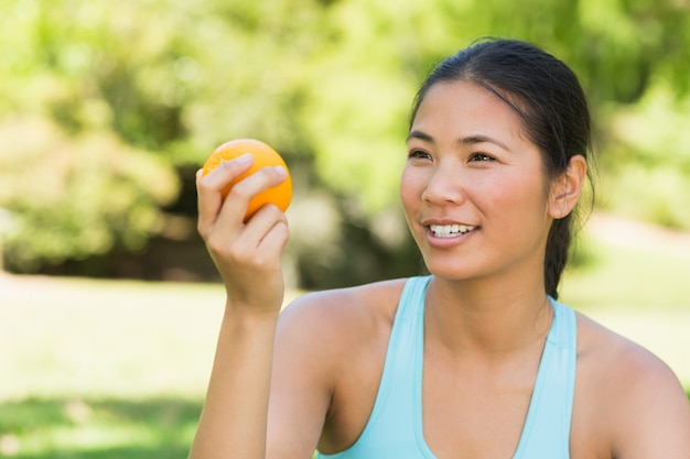 Close-up of woman holding orange in park