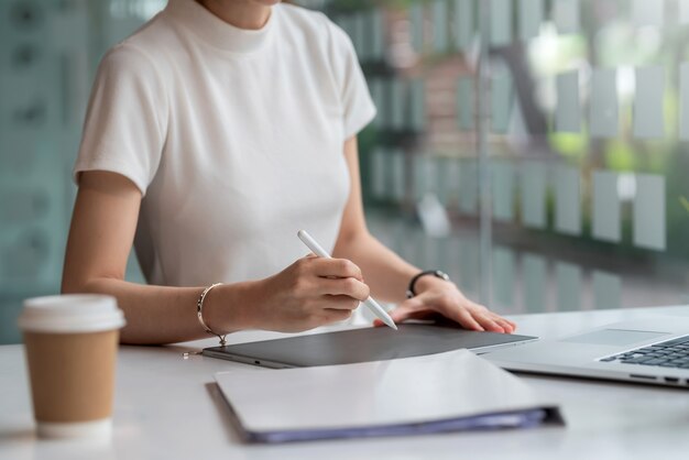 Close up of a woman holding a pen with a tablet at the office.