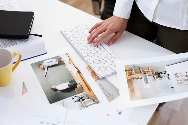 Крупный план женщины, держащей фотографию и использующей компьютерную клавиатуру в офисе