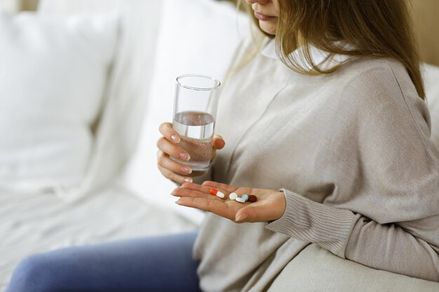 Close-up woman holding pills time to take medications, cure for headache, high blood pressure or cholesterol level remedy pain killer drugs. Medicine concept.