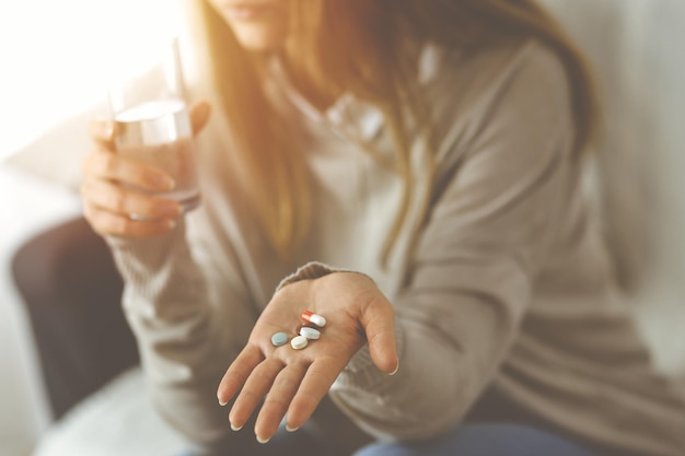 Close-up woman holding pills time to take medications, cure for headache. Medicine concept during self isolation and Coronavirus pandemic.