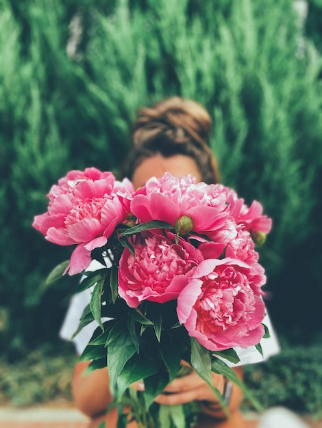 外でピンクの花を持った女性のクローズアップ