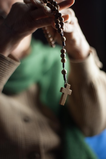 Foto close-up di una donna che tiene il rosario con le mani giunte