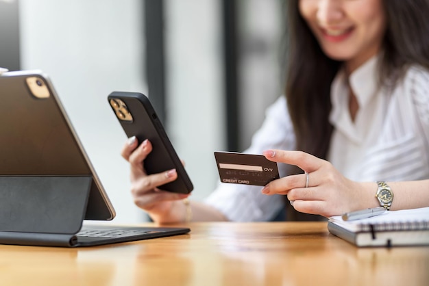 Avvicinamento. donna che tiene smartphone e utilizza la carta di credito per lo shopping online.