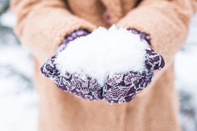 Close up of woman holding snow in hands, winter concept.