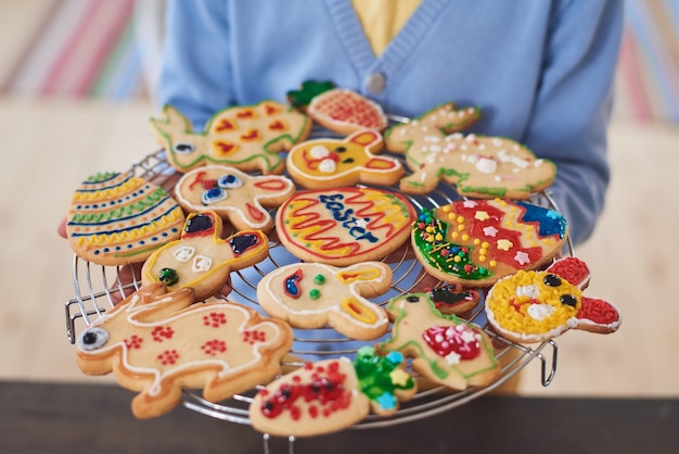 Foto primo piano della donna che tiene il vassoio con i biscotti al forno decorati che si preparano per la pasqua