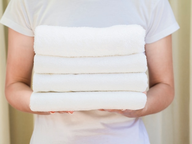 Close-up woman holding white folded clean towels