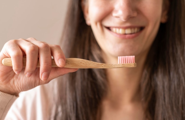 Foto donna del primo piano che tiene spazzolino da denti di legno