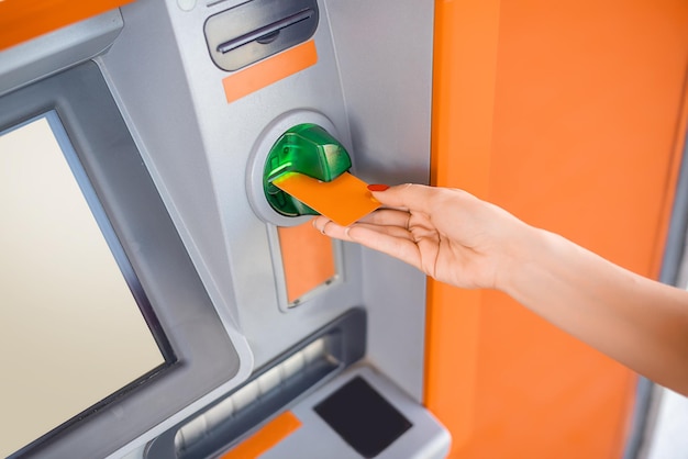 은행 ATM 기계에 신용 카드를 삽입하는 여성의 클로즈업