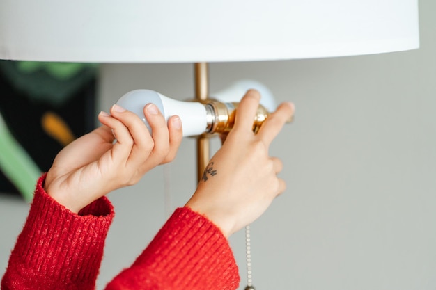 Close up of woman inserts light bulb into chandelier at home