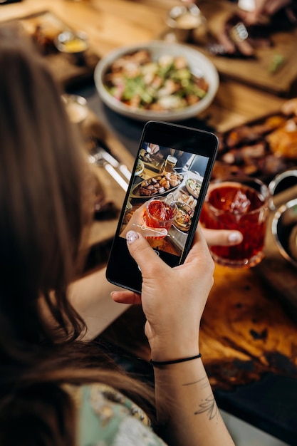 Photo close up of woman is making photo of meal for social networks in restaurant before dinner