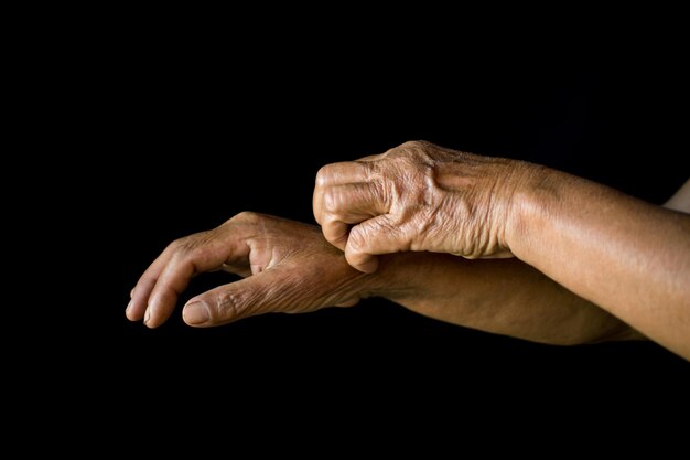 Close-up of woman itching hand against black background