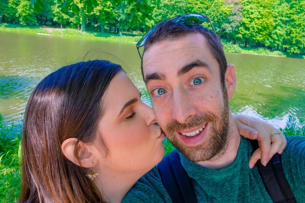 Close-up of woman kissing boyfriend standing against river