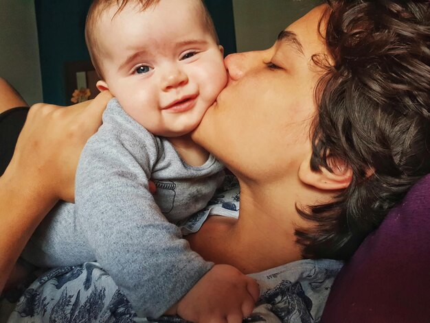 Photo close-up of woman kissing son at home