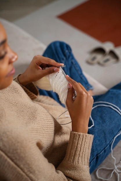 Foto chiuda sulla donna che lavora a maglia con filato bianco