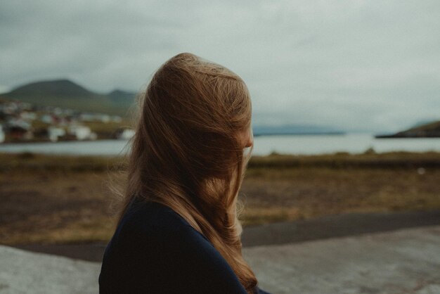 Foto close-up di una donna al lago contro il cielo