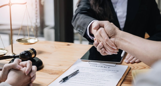 Close up of woman lawyer hand and man client shaking hand\
collaborate on working agreements with contract documents at the\
office