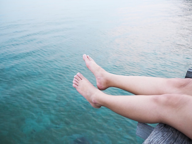 青い海の上に女性の足と足を閉じます。