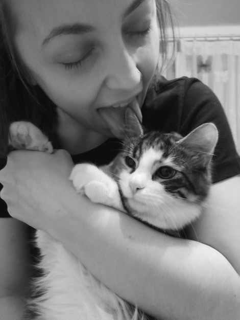 Photo close-up of woman licking cat at home