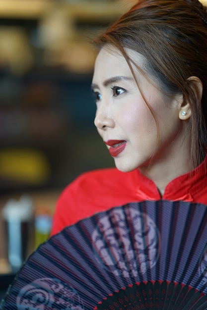 Photo close-up of woman looking away while holding hand fan