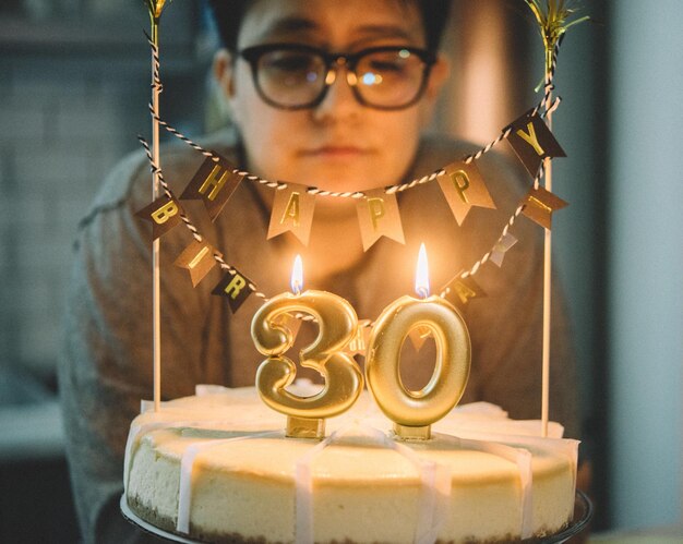 Foto close-up di una donna che guarda la candela numero 30 che brucia il suo compleanno