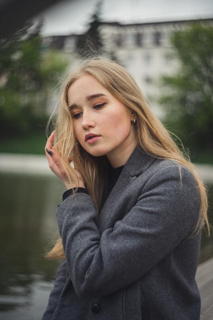 Фотография клоуз-ап женщины, смотрящей вниз, сидя на открытом воздухе