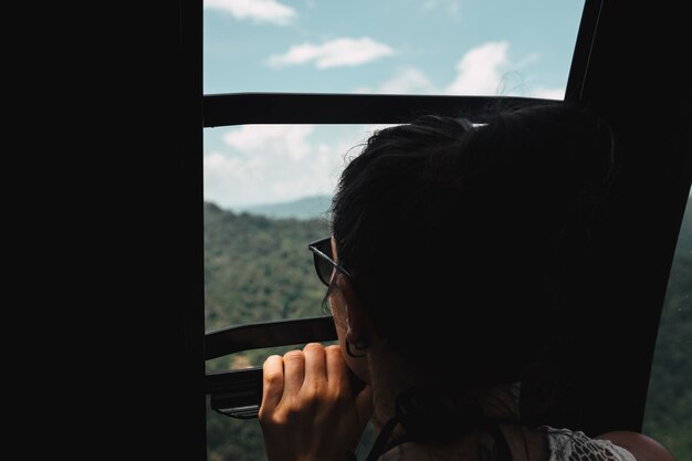 Foto close-up di una donna che guarda il paesaggio attraverso la finestra