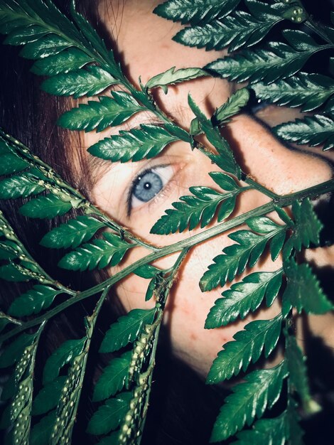 Foto close-up di una donna che guarda attraverso le foglie di notte