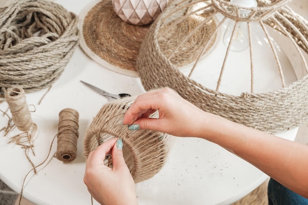 Close up Woman makes handmade diy lamp from jute rope at home