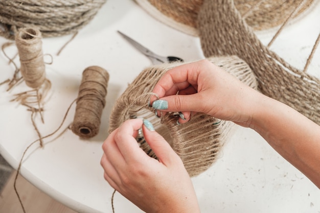 Close up Woman makes handmade diy lamp from jute rope