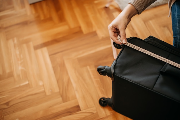 Close-up of woman measuring luggage.