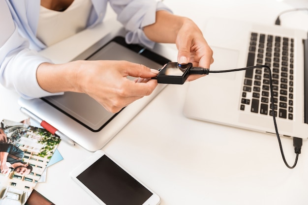 Close up of a woman photographer connecting hard disk drive to a laptop over table