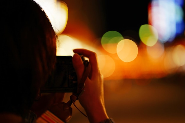 Foto close-up di una donna che fotografia una strada della città di notte