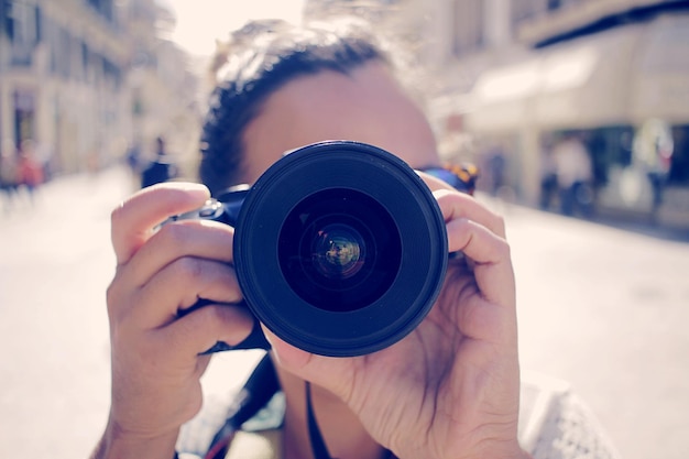 close-up of woman photographing from camera on street