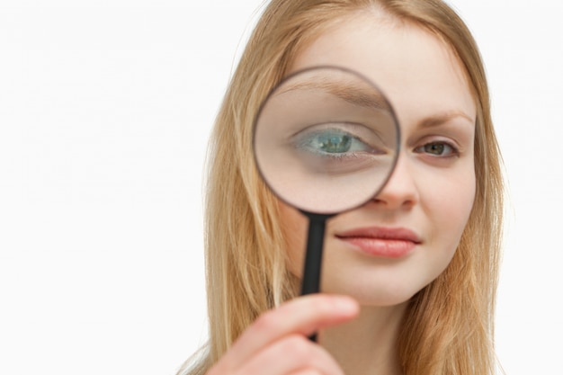 Close up of a woman placing a magnifying glass on her eyes