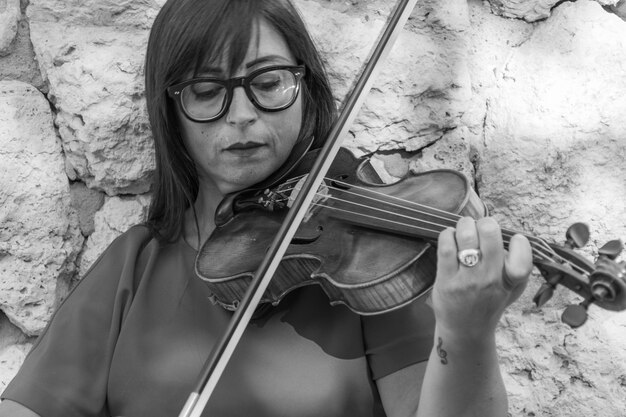 Photo close-up of woman playing violin against wall