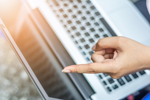 Photo close-up of woman pointing at laptop