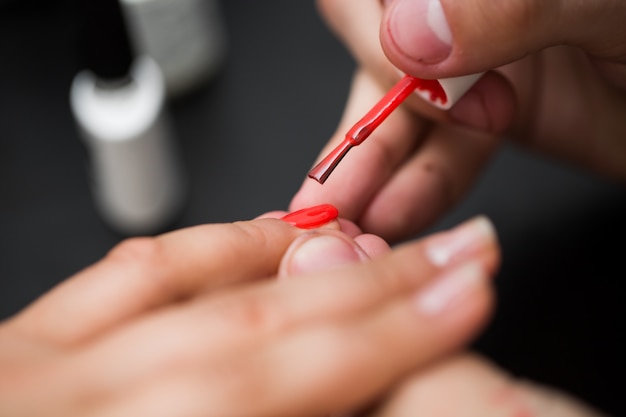 Close-up of woman polishing nails with red nail polish in a beauty salon