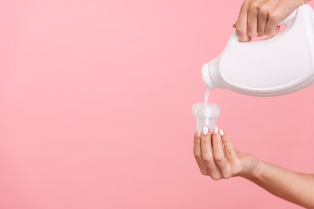 Photo close-up woman pouring detergent in cap