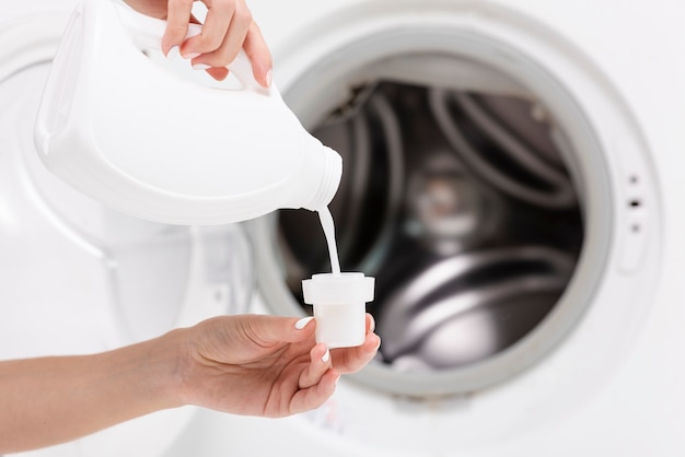Photo close-up woman pouring detergent with washing machine