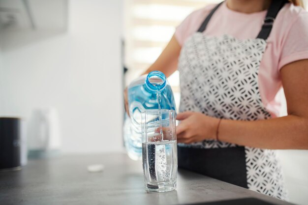 Foto primo piano di una donna che versa acqua fresca in cucina