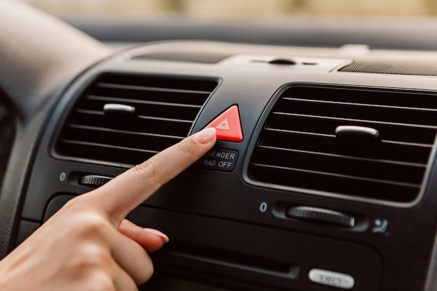 Photo close up woman press emergency gang red button accident black dark car interior dashboard display